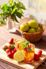 Refreshing summer drink with lemon, strawberry and mint on wooden table