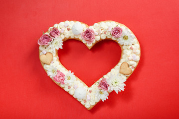 Valentine's Day heart-shaped cake with flowers as decoration. The concept of a gift to a loved one on a holiday.