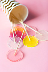 multi-colored lollipops on a pink background in a paper golden glass