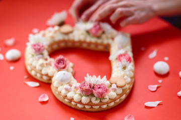 Valentine's Day heart-shaped cake with flowers as decoration. The concept of a gift to a loved one on a holiday.