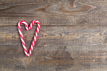 candy canes in heart shape on wooden background