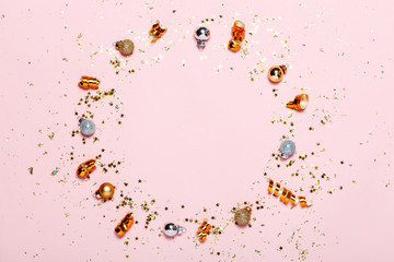 Christmas background with golden decorations put as frame on pink pink background. Bright and festive flat lay. Top view, Copyspace for text. Greetings for christmas or new year.
