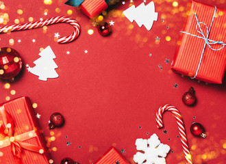 Red christmas Background with holiday decorations, fir brances, christmas candies and Merry Christmas text.
