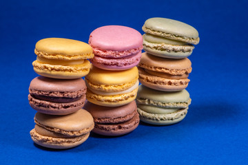 Colorful french macarons isolated on blue background. Pastel colors - Imagen