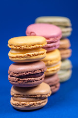 Colorful french macarons isolated on blue background. Pastel colors - Imagen