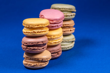 Colorful french macarons isolated on blue background. Pastel colors - Imagen