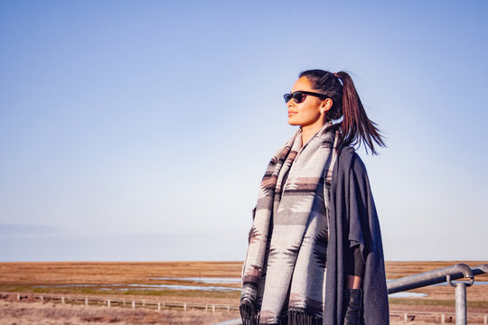 Young female model with tunic and sunglasses in front of the fields in Northern Germany.