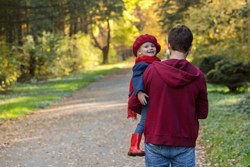 Fototapeta premium Father hugs daughter in autumn day. Back view, copy space.