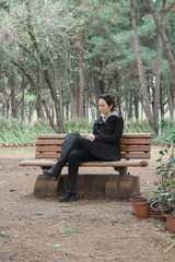 Fototapeta premium Girl sitting on a banch in the woods