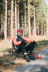 Training an athlete on the roller skaters. Biathlon ride on the roller skis with ski poles, in the helmet. Athlete is getting ready to start. Autumn workout. Roller sport.