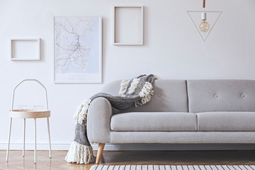 Stylish and cozy scandinavian white interior with design, coffee table, pillows, blanket, gramophone and mock up photo frames. White background walls and modern triangle lamp. 