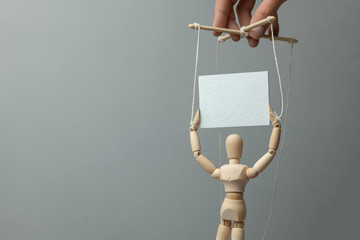 Puppeteer rules the doll on the ropes which holds the poster. The concept of rally or demonstration...