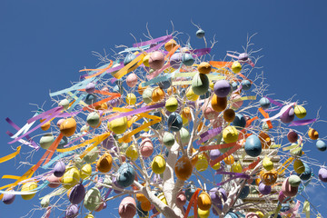Easter Colored Eggs With Ribbons On Easter Festive White Tree On Blue Sky Background. Symbol Of...
