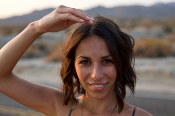 Beautiful young woman looking right at camera with hand on head