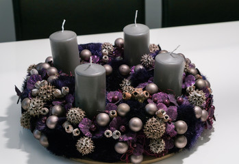 Obraz na płótnie Canvas Purple advent wreath with baubles and four grey candles on a white table