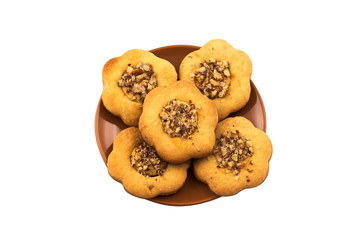 Homemade chamomile cookies with chopped nuts. Round porcelain brown plate. Isolated on white background.
