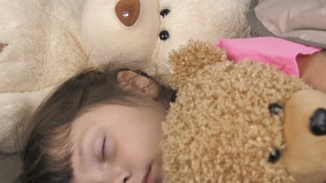 Portrait of a beautiful sleeping child. Little girl sleeps with toy cubs.
