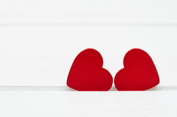 Fototapeta premium Two red wooden hearts on white wooden background. Valentine's day or Love concept.