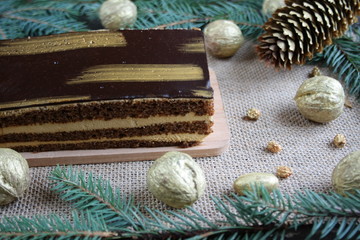 Fototapeta na wymiar Golden cake among Christmas decorations, golden nuts, rowan and cones