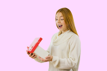 Attractive red-haired girl who smiles into the camera and shows a box with a gift, gives a gift, New Year, Christmas, Valentine's Day on isolated background