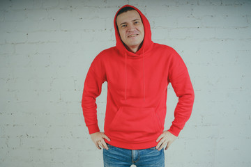 Handsome guy posing by a brick wall. Crazy man in a red hoodie - Powered by Adobe