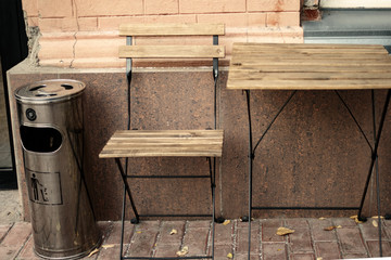 Wooden table and chair outside cafe with litter bin