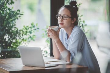 Asian girls drinking coffee on the desk at home.