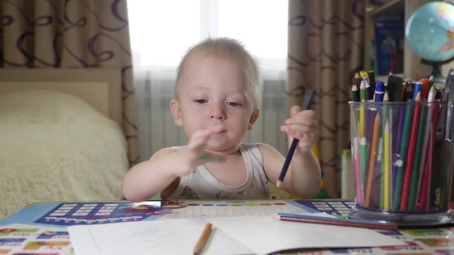 Cute kid boy painting at home, 1 year old toddler baby boy child painting with pencils, happy preschooler. Creative play for toddlers concept.