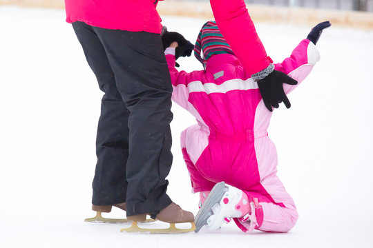 the girl helps the child to skate ice