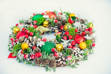 Beautiful traditional bright Christmas wreath decorated with pine cones, spruce branches,berries, balls, stars, decorative beers on white background isolated. Close up, selective focus. Copy space.