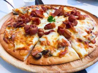 Carbonara Pizza with Smoked bacon, Ham, Mushroom, Cherry Tomato, Egg, Cheese and Cream Sauce that was placed on the wooden dish. This is a popular Italian cuisine
