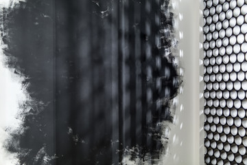 White and black wall with shadows on it and a gray partition made of short pipes