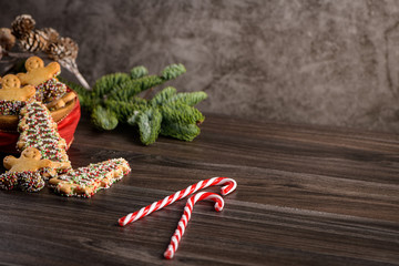 Christmas holiday background with gingerbread cookies, candy canes and evergreens over wooden table. Christmas and New year food. Christmas decoration and sweets on wood background.