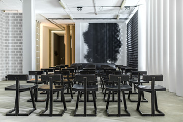lot of the black wooden chairs between the white glowing columns