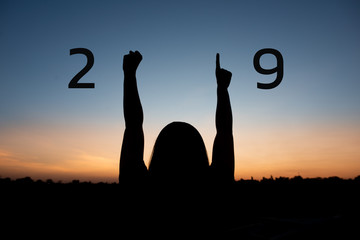 Silhouette of happy woman with New year 2019 concept on sunset background.