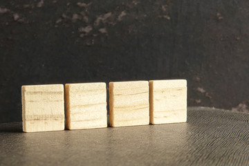 Blank wood scrabble pieces isolated on grunge black background.