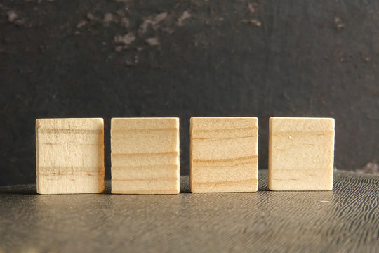 Blank wood scrabble pieces isolated on grunge black background.