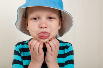 Portrait of funny boy in blue hat and striped sweater with different emotions.