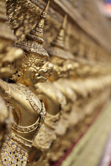 group of golden Garuda statue stand around , the bronze symbol of Thai government, giant ancient gold eagle with crown sculpture antique signature on temple royal palace wall
