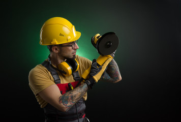 a young man posing on a black background in a work uniform and a construction tool
