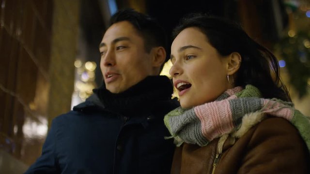 Young attractive mixed race couple shopping outdoors at night at Christmas time