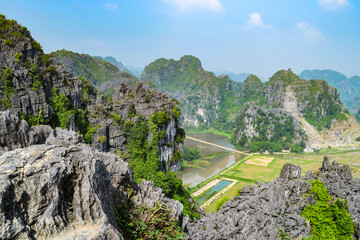 Fototapeta na wymiar Hang Mua Mountain viewpoint or Mua Caves Ecolodge, Stunning view of Tam Coc area with mountain range, rice fields and waterway.