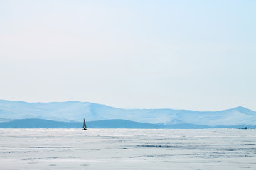 Ice boat rides on the ice of Lake Baikal in the background Olkhon in the winter foggy morning away