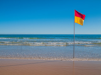 Beach with red and yellow flag indicating safe, patrolled beach in Australia