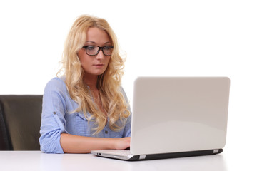 Concentrated young beautiful businesswoman working on laptop in bright modern office