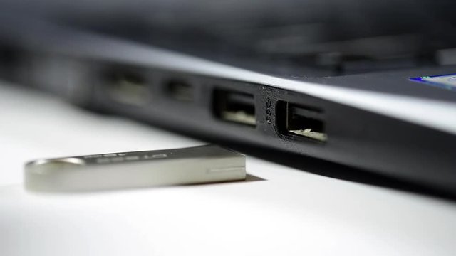 Caucasian man hand pulls out usb pen drive from laptop computer.