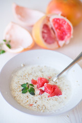 sweet oatmeal with slices of red grapefruit in a ceramic bowl