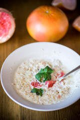 sweet oatmeal with slices of red grapefruit in a ceramic bowl