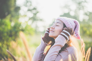 Beautiful young woman in warm knit clothes and earmuff, with a relaxed morning in a warm meadow.