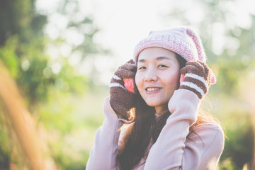 Beautiful young woman in warm knit clothes and earmuff, with a relaxed morning in a warm meadow.